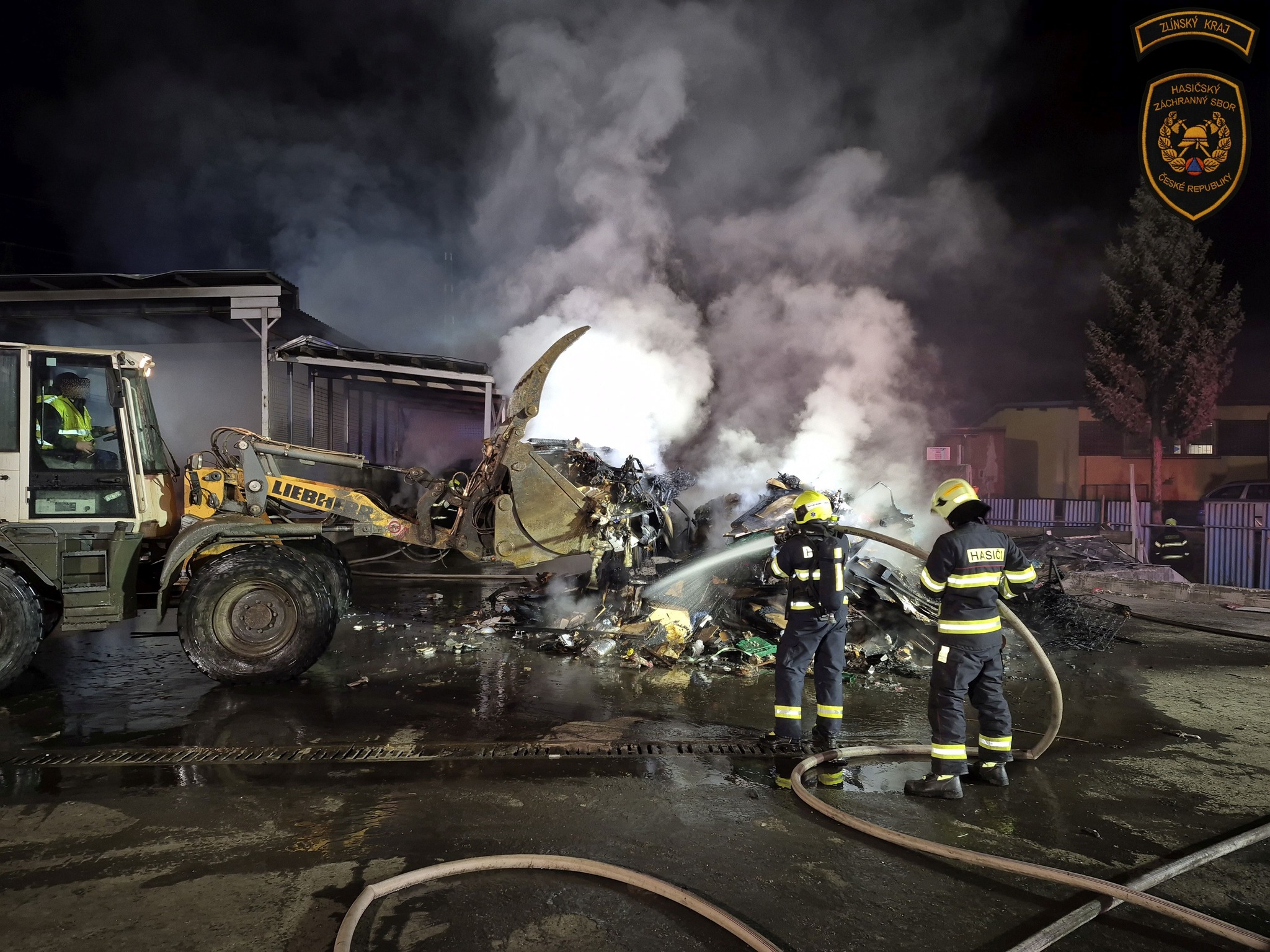 Nakladač vyvážel hořící materiál na betonovou plochu, kde jej hasiči dohašovali.